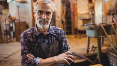 Portrait of glassblower standing with arms crossed at glassblowing factory