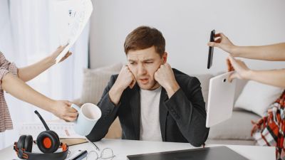Many hands reach out to a man with various objects